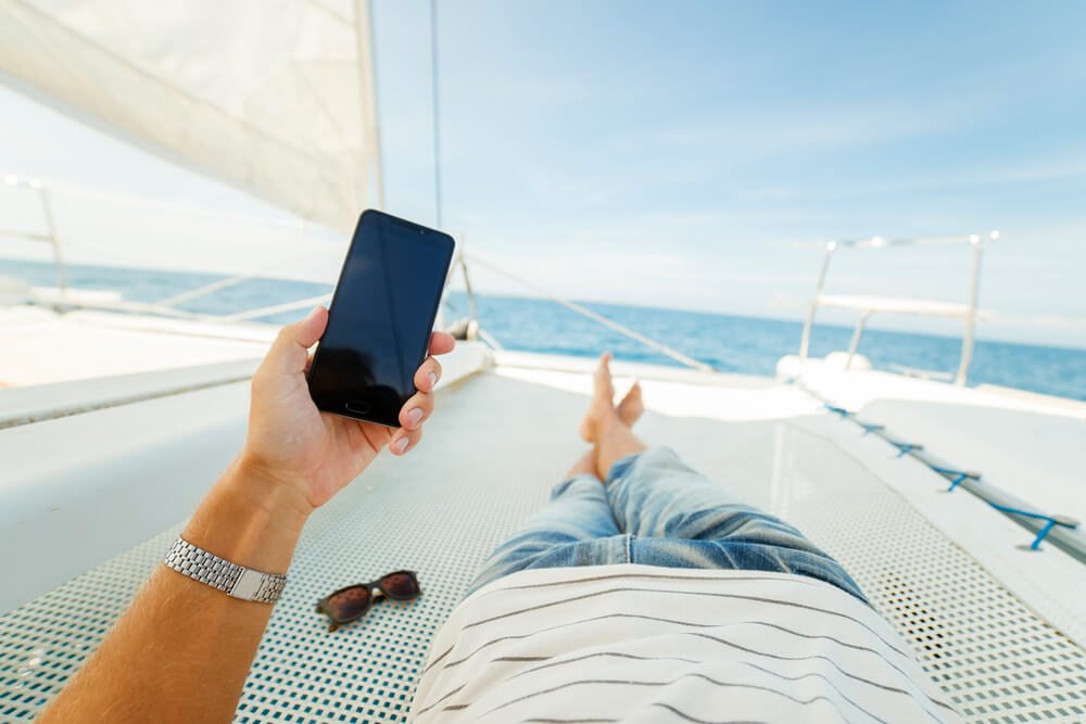 Muž relaxující na lodi s telefonem v ruce
