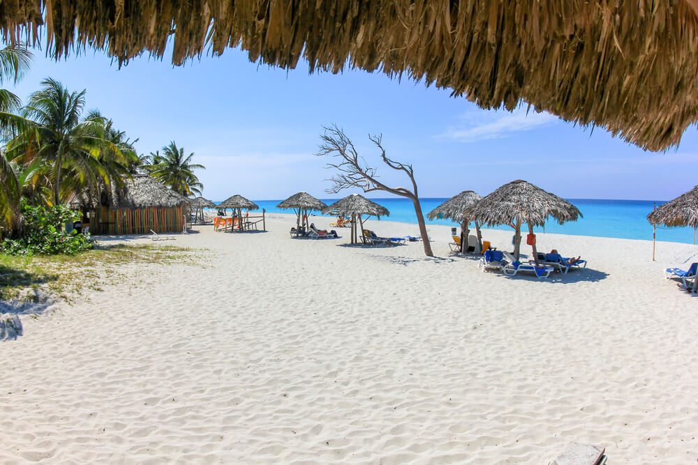 Písečná pláž se slunečníky na Kubě
