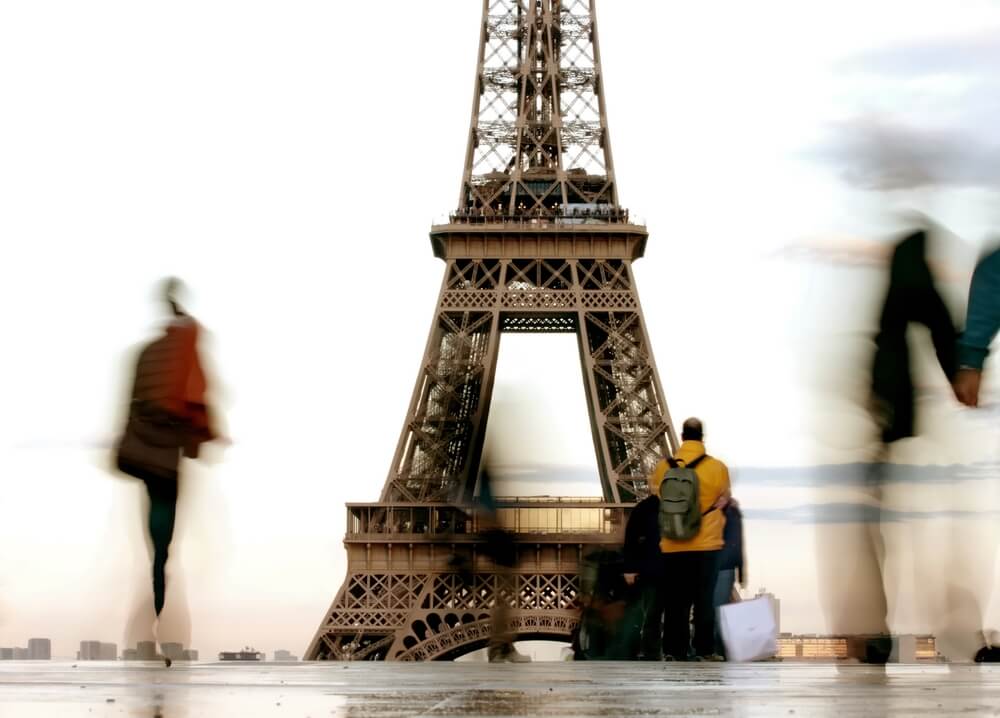 Lidé chodící kolem Eiffelovy věže.