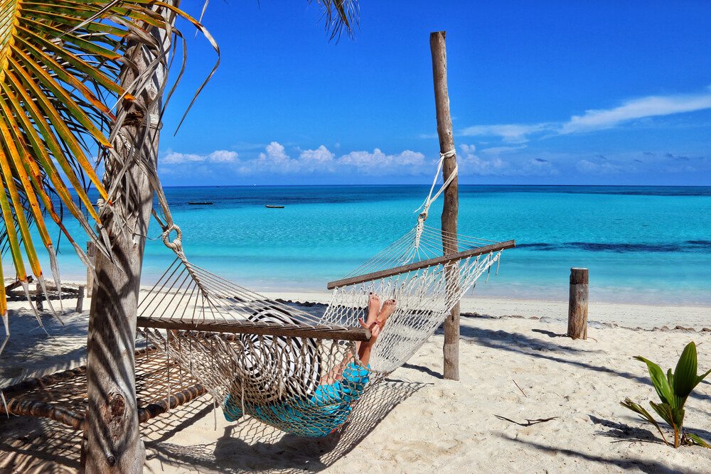 Žena relaxuje v houpací síti na pláži na Zanzibaru