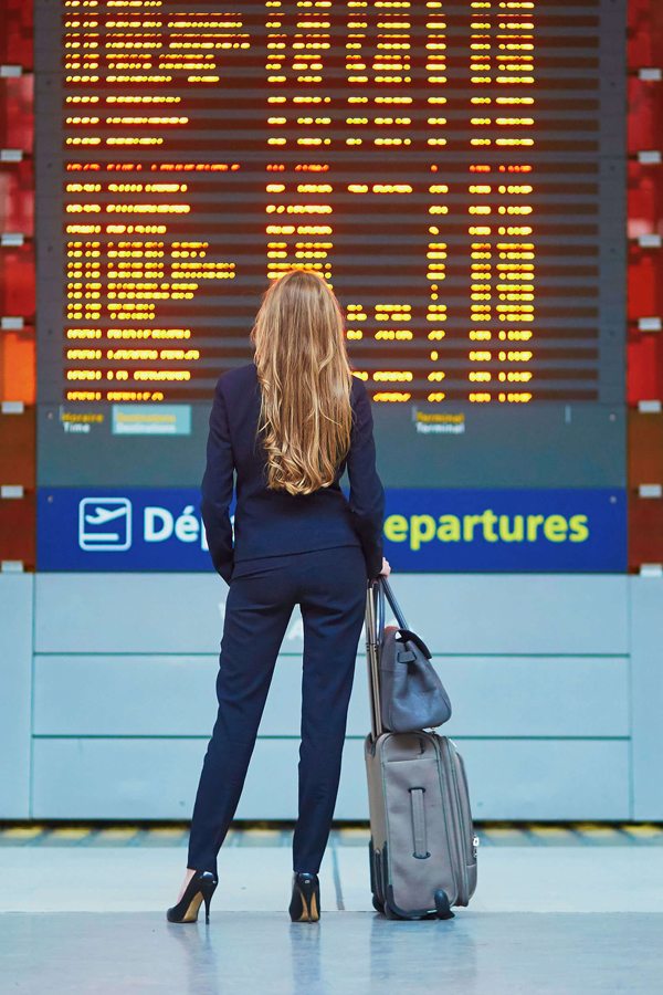 Žena na letišti, sledující informační tabuli.