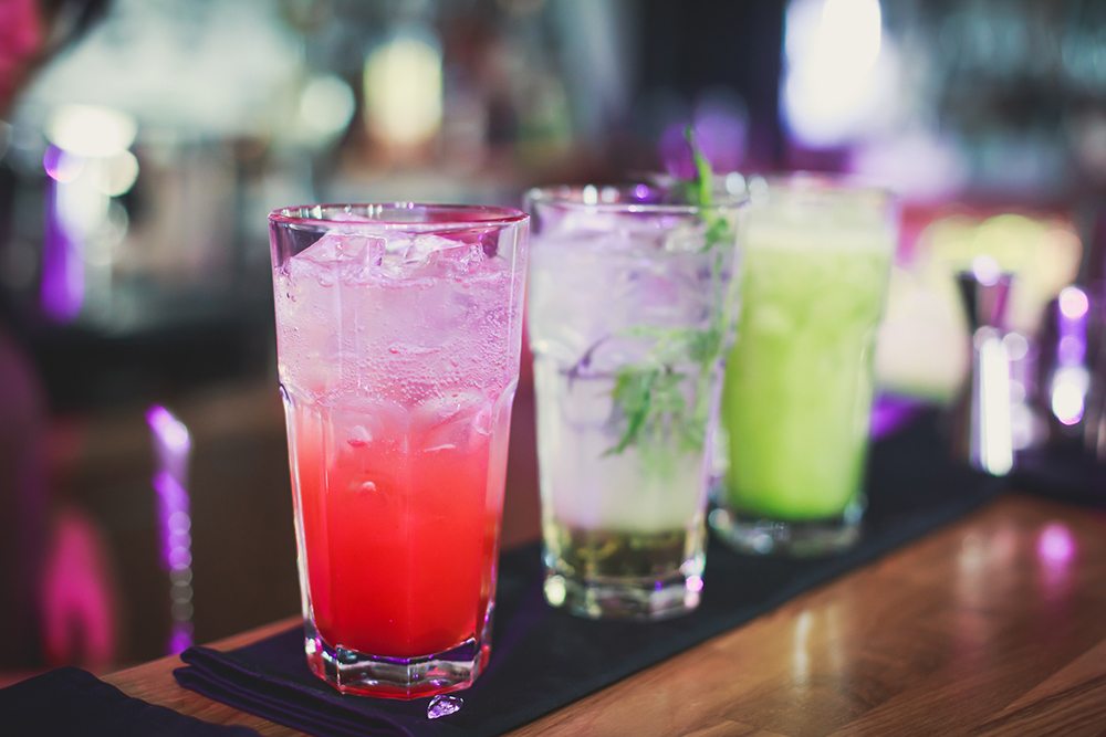 Řada různobarevných sklenic na baru.
