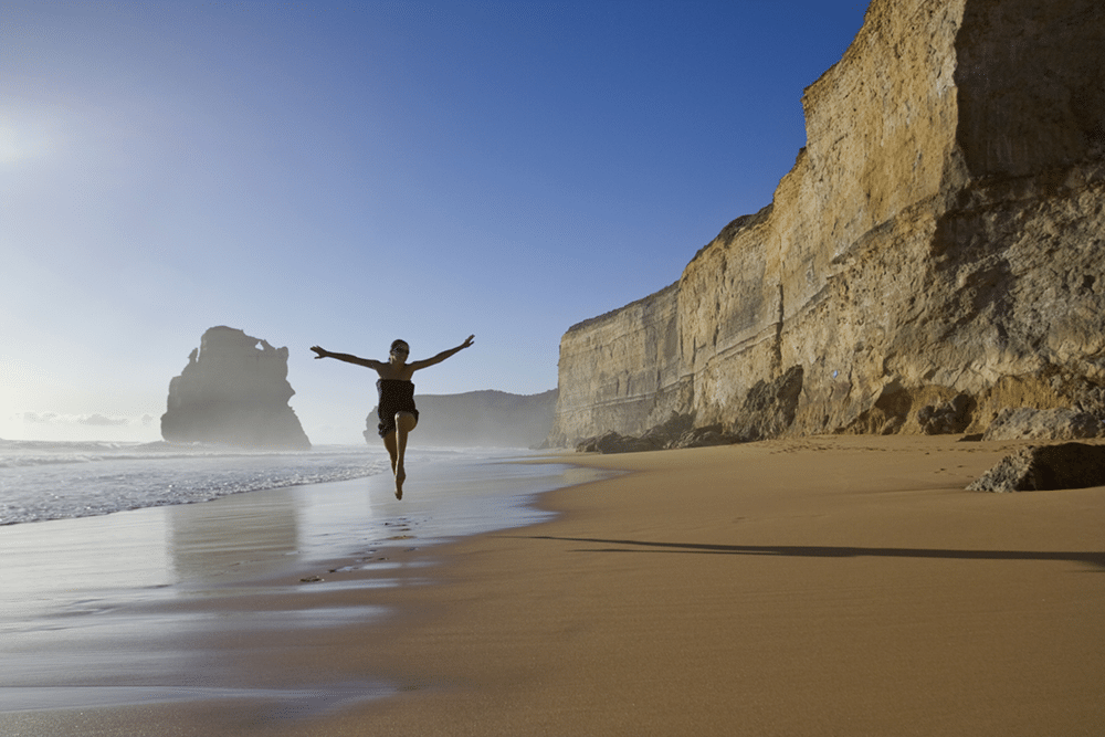 Žena poskakující na pláži.