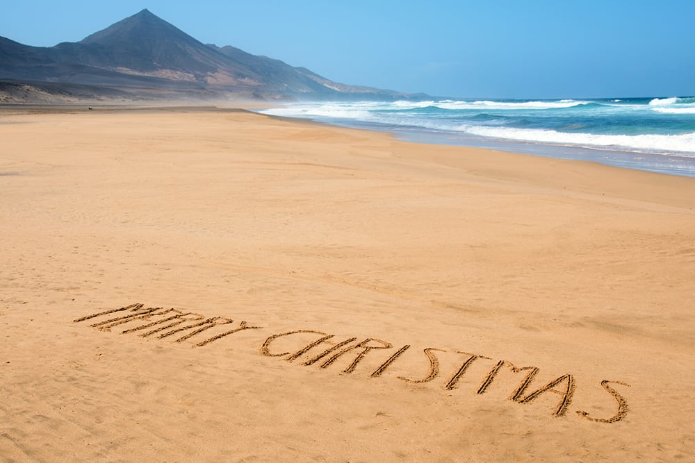 Nápis Merry Christmas v písku na pláži.
